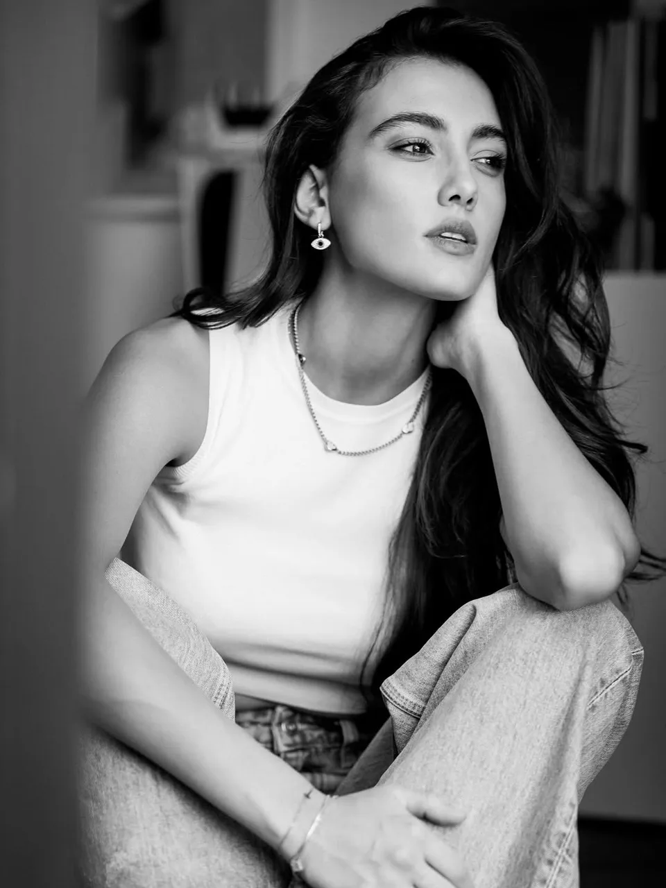 Zeudi assise en haut blanc sans manches et en jean, photographiée en noir et blanc.